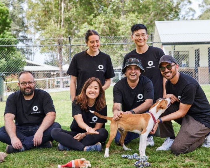 Macquarie employees at a Macquarie Foundation event sitting with a dog