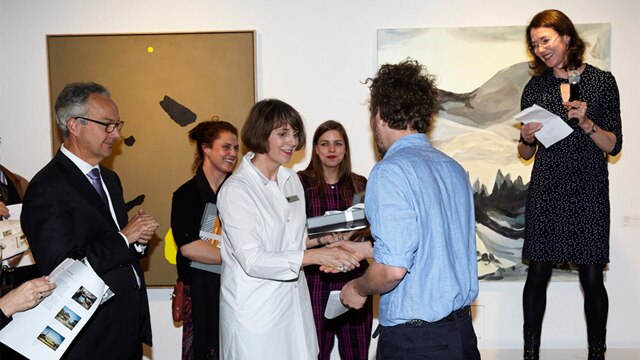 Winner Aaron Carter receiving his prize from (L-R), Nicholas Moore, CEO Macquarie Group, Helen Burton, Director, Macquarie Group Collection and (on platform) guest judge Louise Hearman.