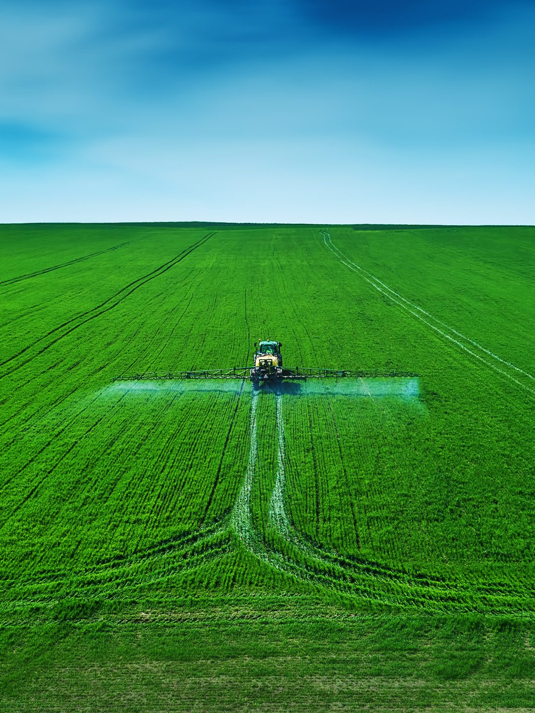wide shot of tractor spraying lush green paddock