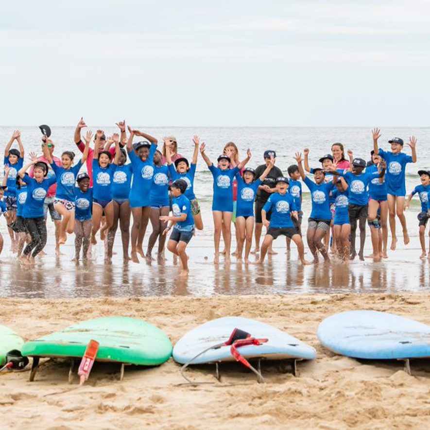 Children with surfboards at the beach at a Macquarie Sports sponsored event.
