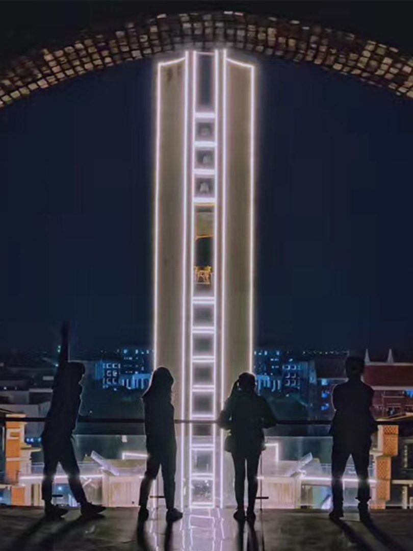 silhouette of four people standing at a rail in front of a brightly lit building