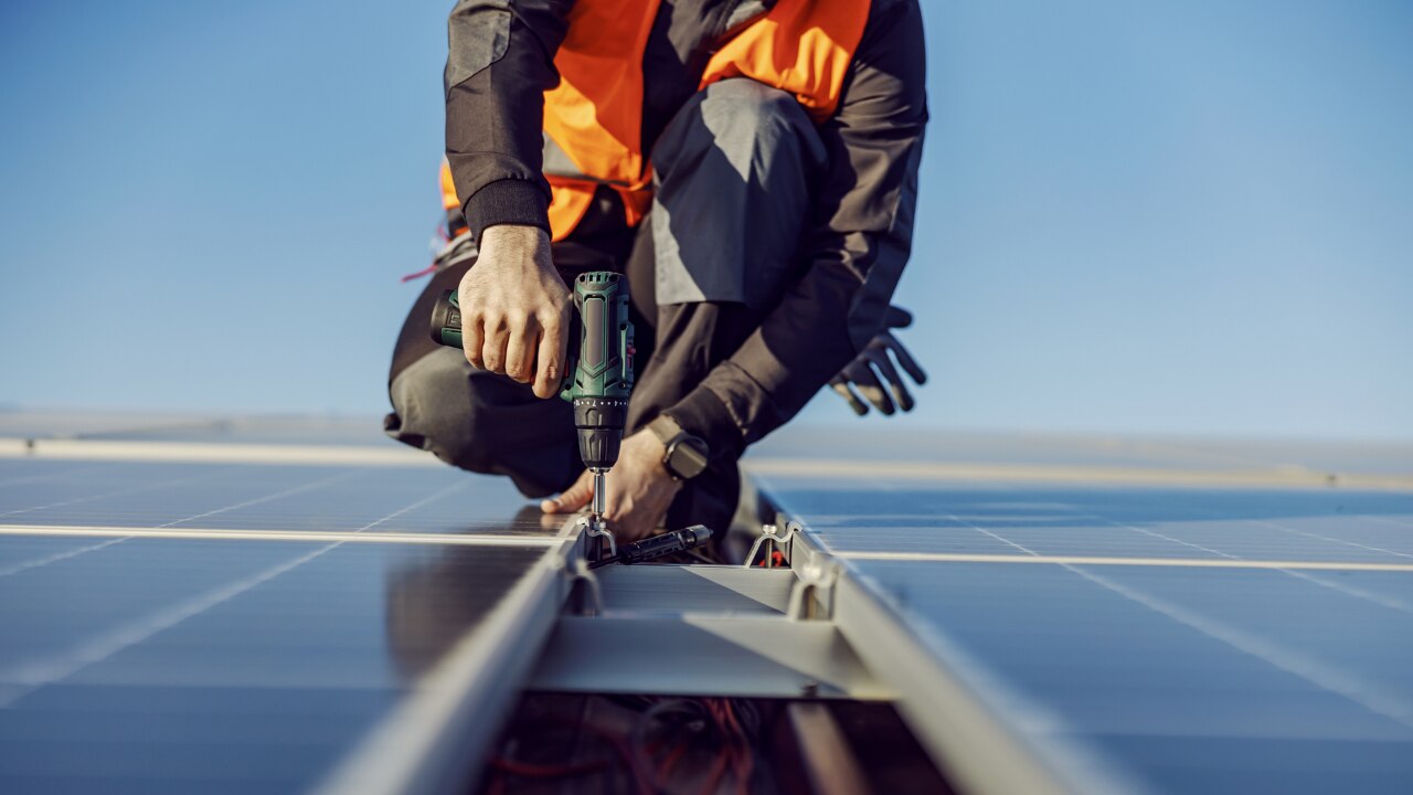 Close up of a Solar Panel Contractor installing solar panels on roof