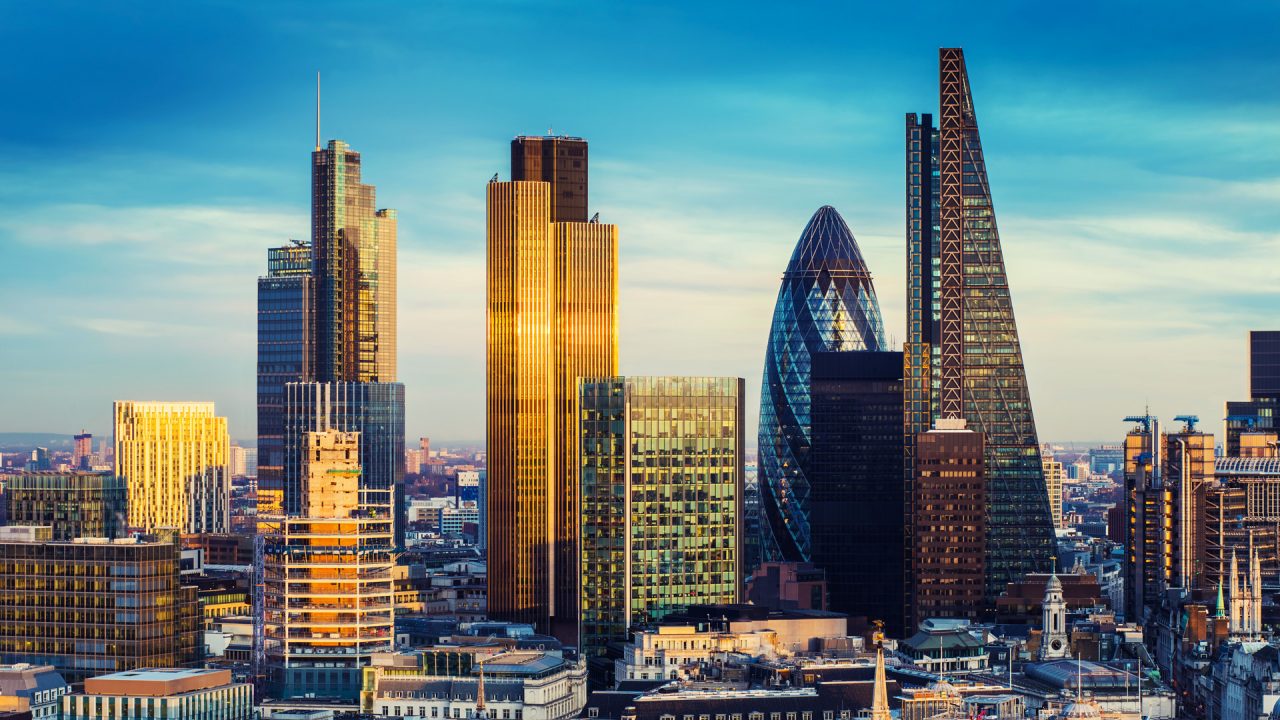 London, United Kingdom - The bank district of central London with famous skyscrapers in golden shine and other landmarks at sunset with blue sky