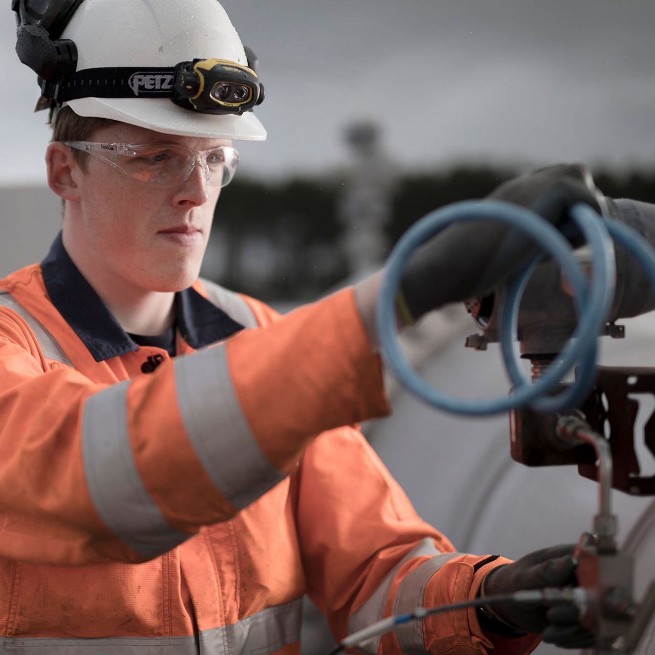 A male factory worker in a high visibility shirt working with a compressor in Aberdeen, Scotland