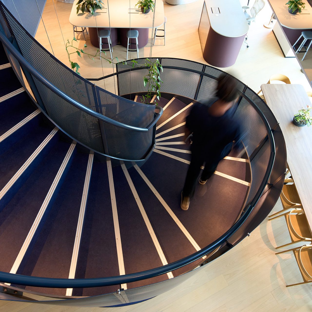 Man walking down spiral staircase in corporate office