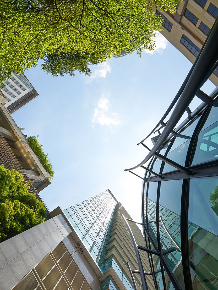 Low angle shot of modern glass buildings and green with clear sky background.