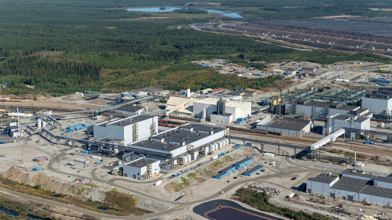 high angle of industrial facility with trees and lake in background