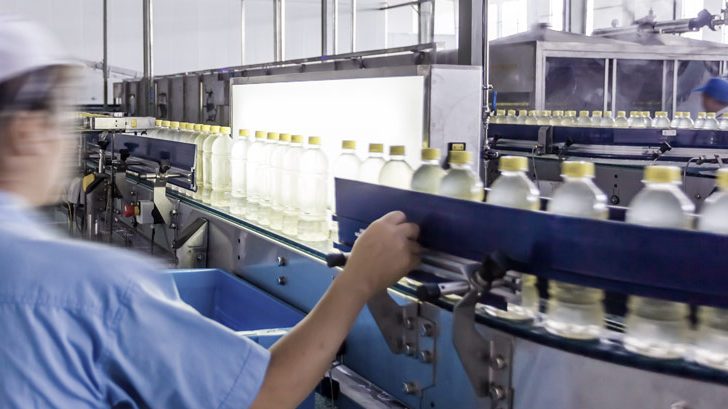 Man quality checking bottles on a conveyor