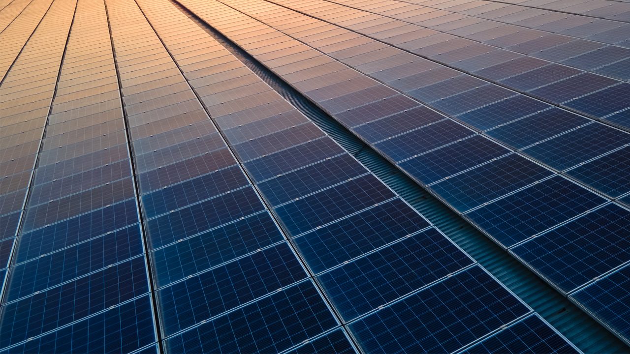 Blue photovoltaic solar panels mounted on building roof for producing clean ecological electricity at sunset. Production of renewable energy concept.