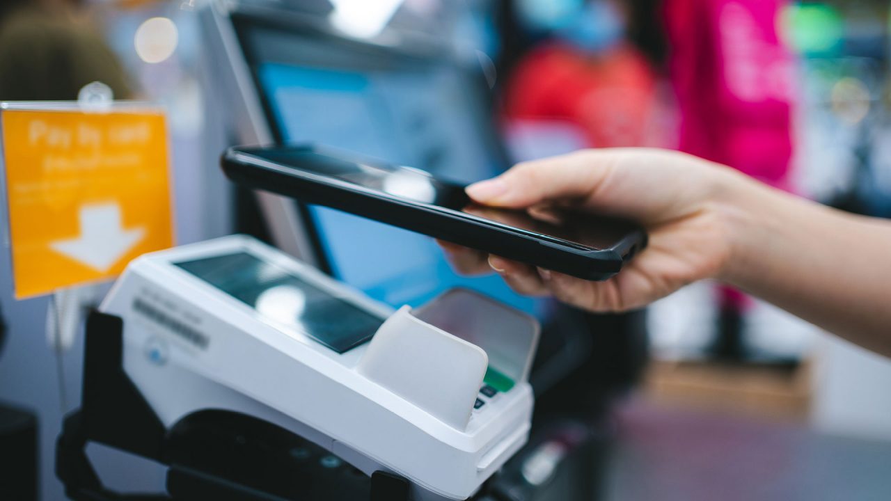 person using phone to pay at self-serve register with eftpos machine