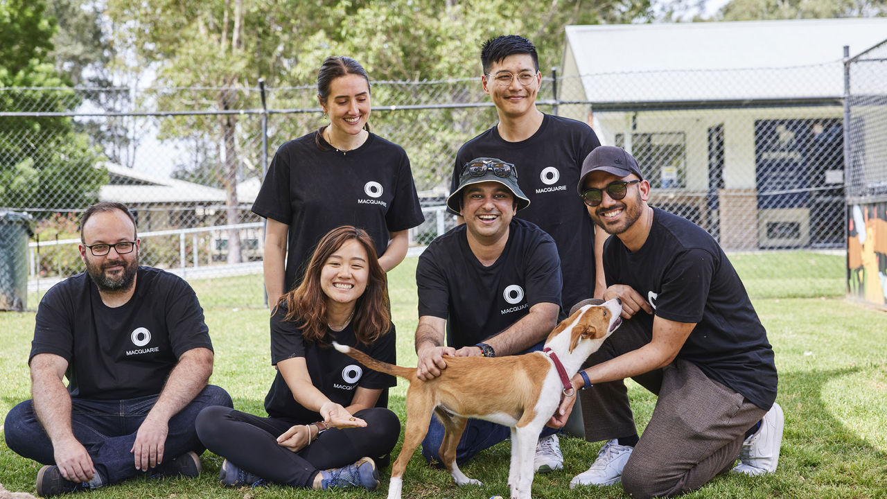 Macquarie employees at a Macquarie Foundation event sitting with a dog