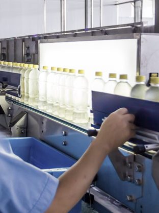 Man quality checking bottles on a conveyor
