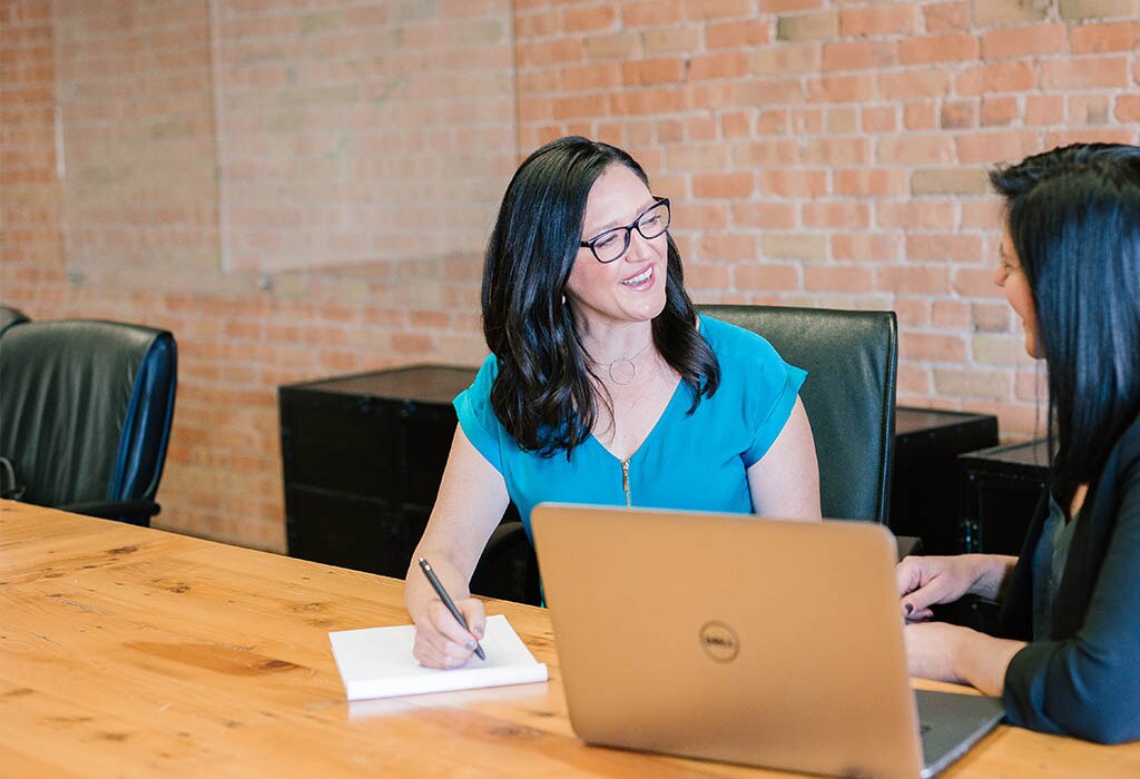 Two business women conversing in conference room