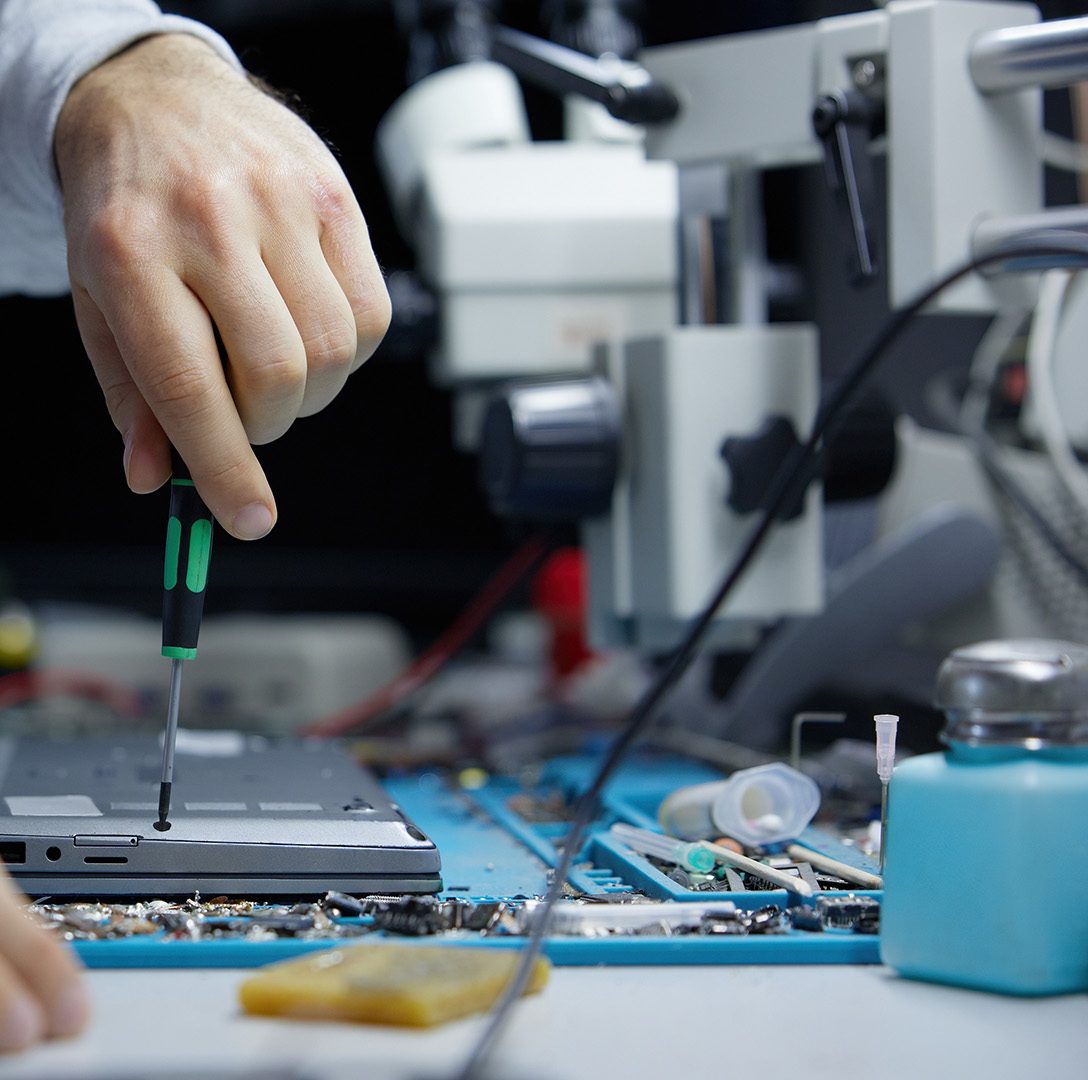 Person repairing a laptop with a screwdriver