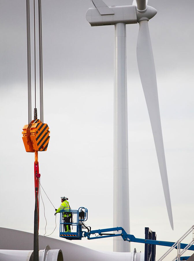 A man on a crane fixing a wind turbine