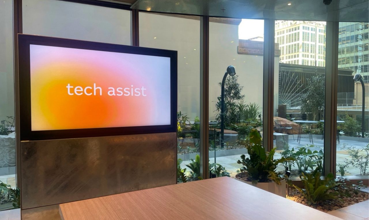 Tech Assist logo on a flatscreen in a indoor garden setting
