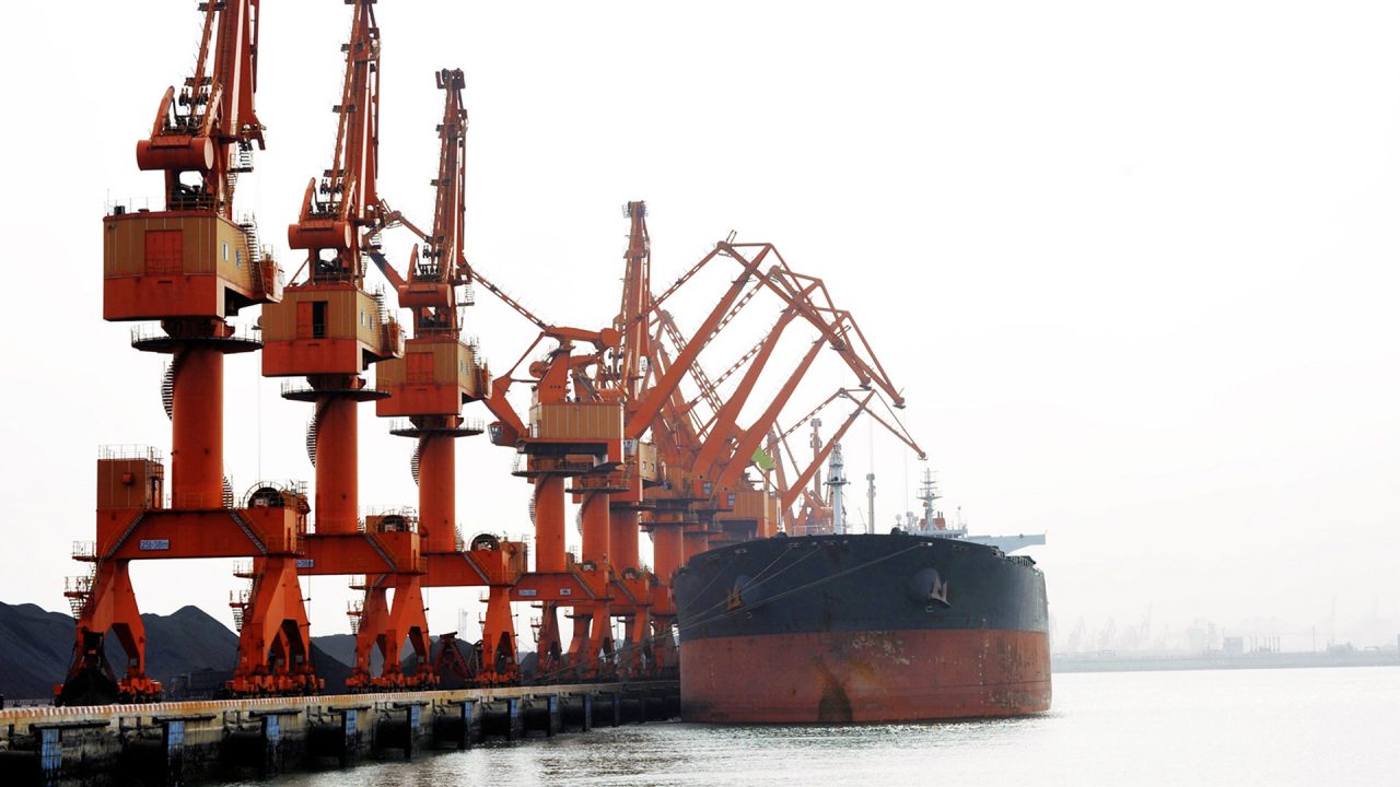 large boat docked at port with many orange cranes lined up on the port