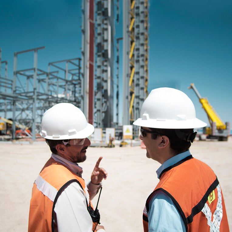 Two construction workers confer outside the Norte site