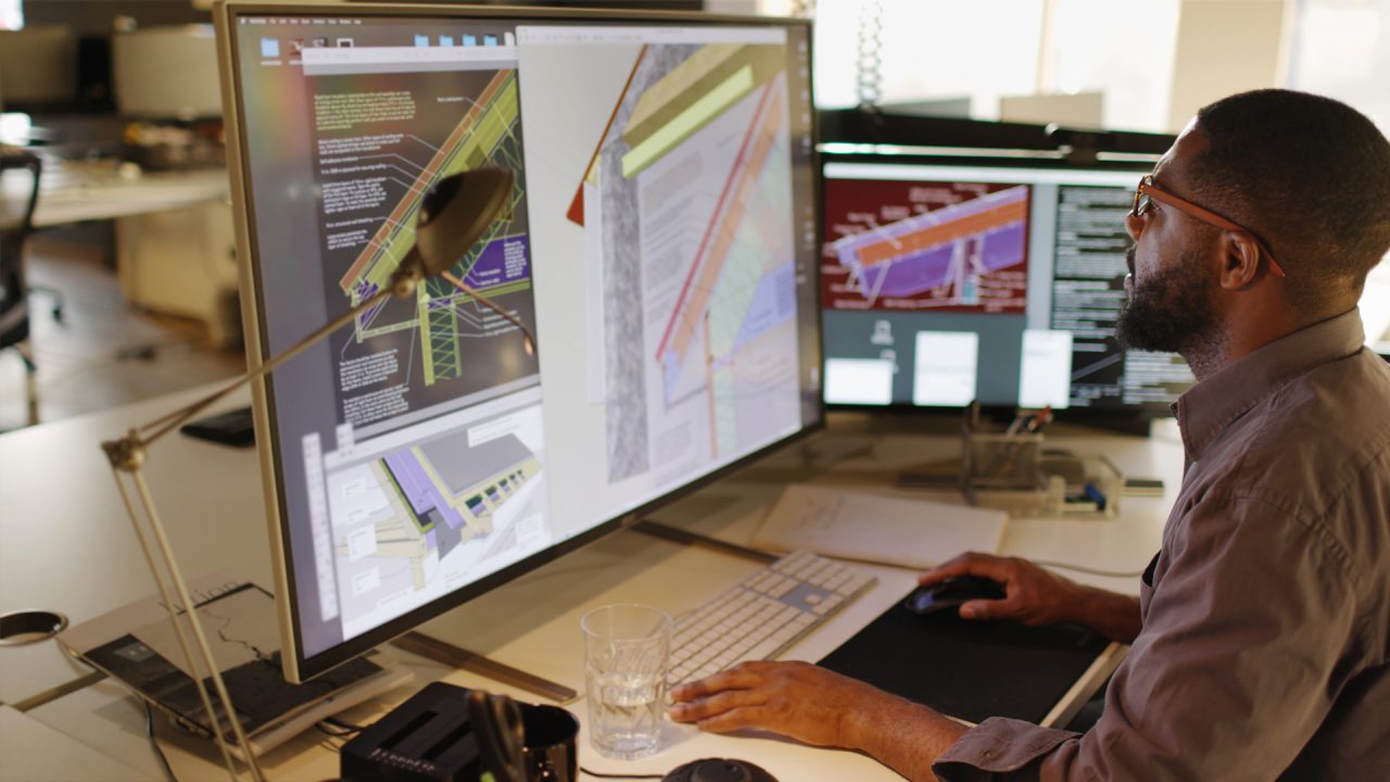 Person working  with designs on a large computer monitor