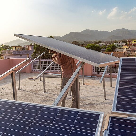 Man installing solar panel in an Indian village