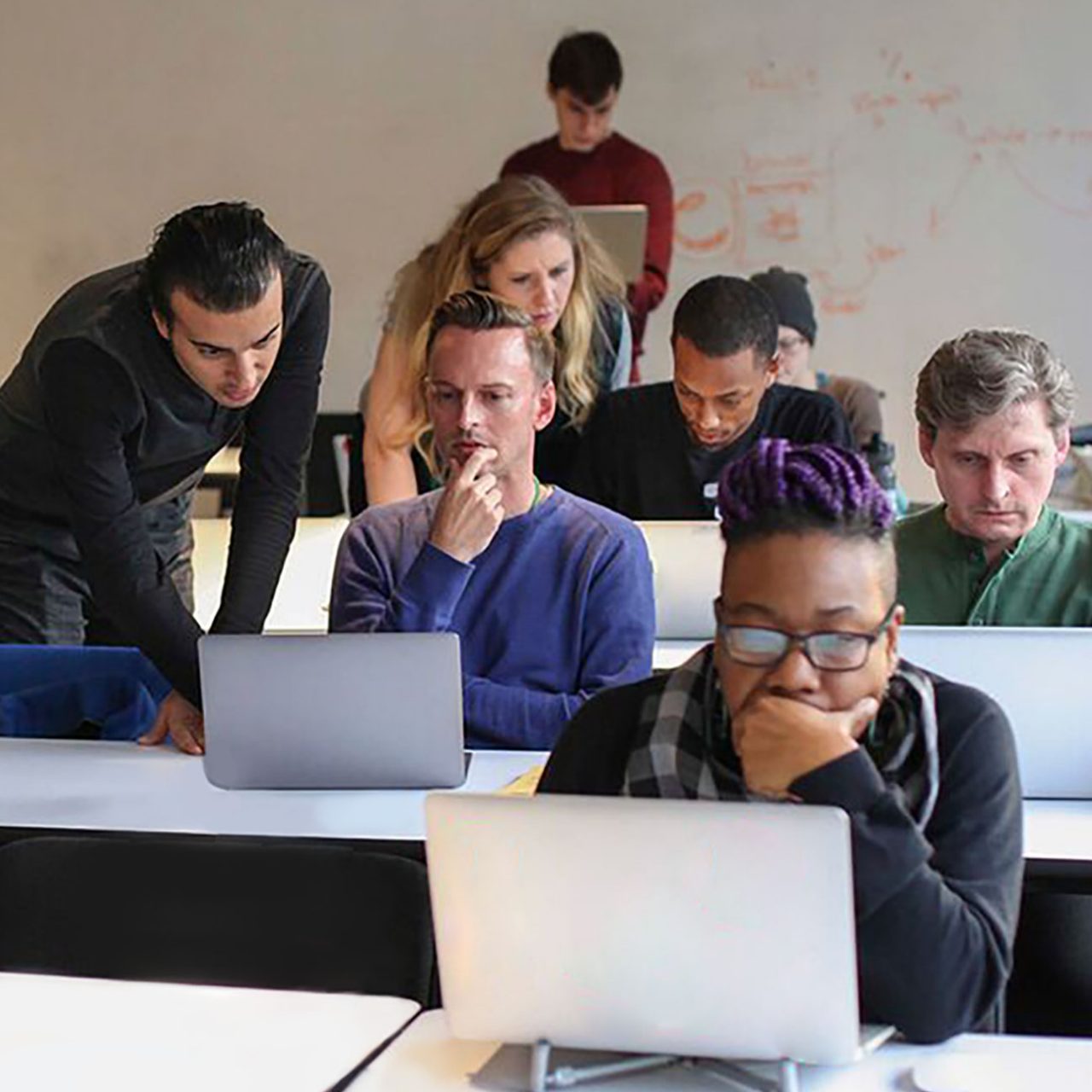 Classroom setup with adults seated at desks looking at laptop computers