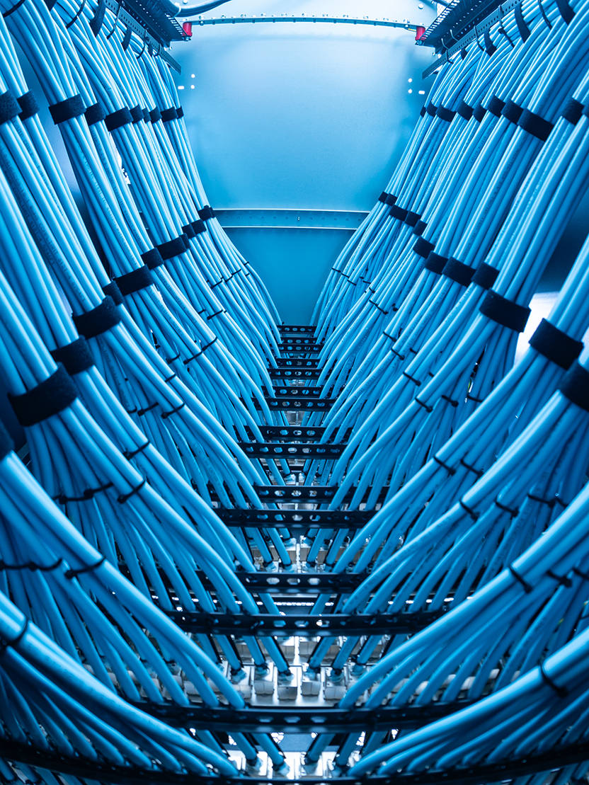 A captivating view of a modern data center showcasing a complex arrangement of blue cables. This interior captures the essence of high-tech communication infrastructure.