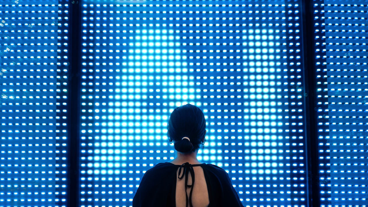 Person looking at an illuminated digital display, using screen of AI technology.