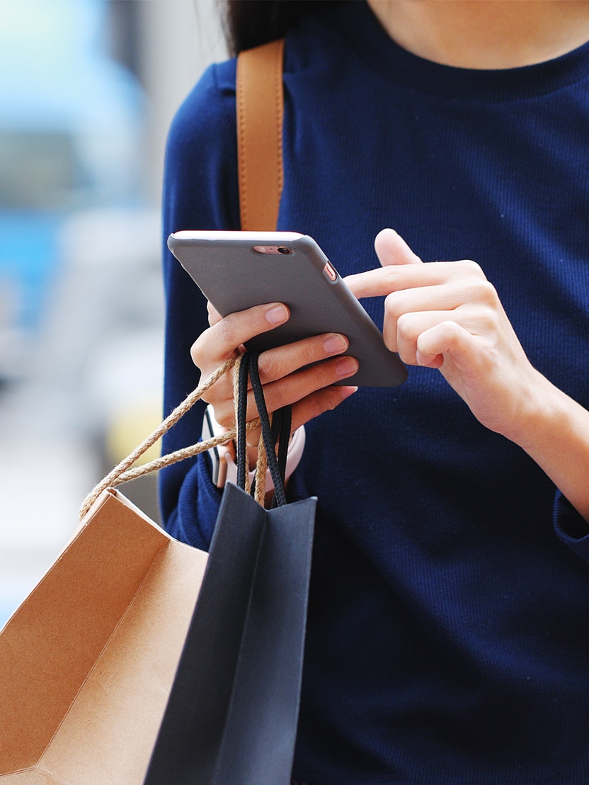 Woman holding paper bag and use of mobile phone
