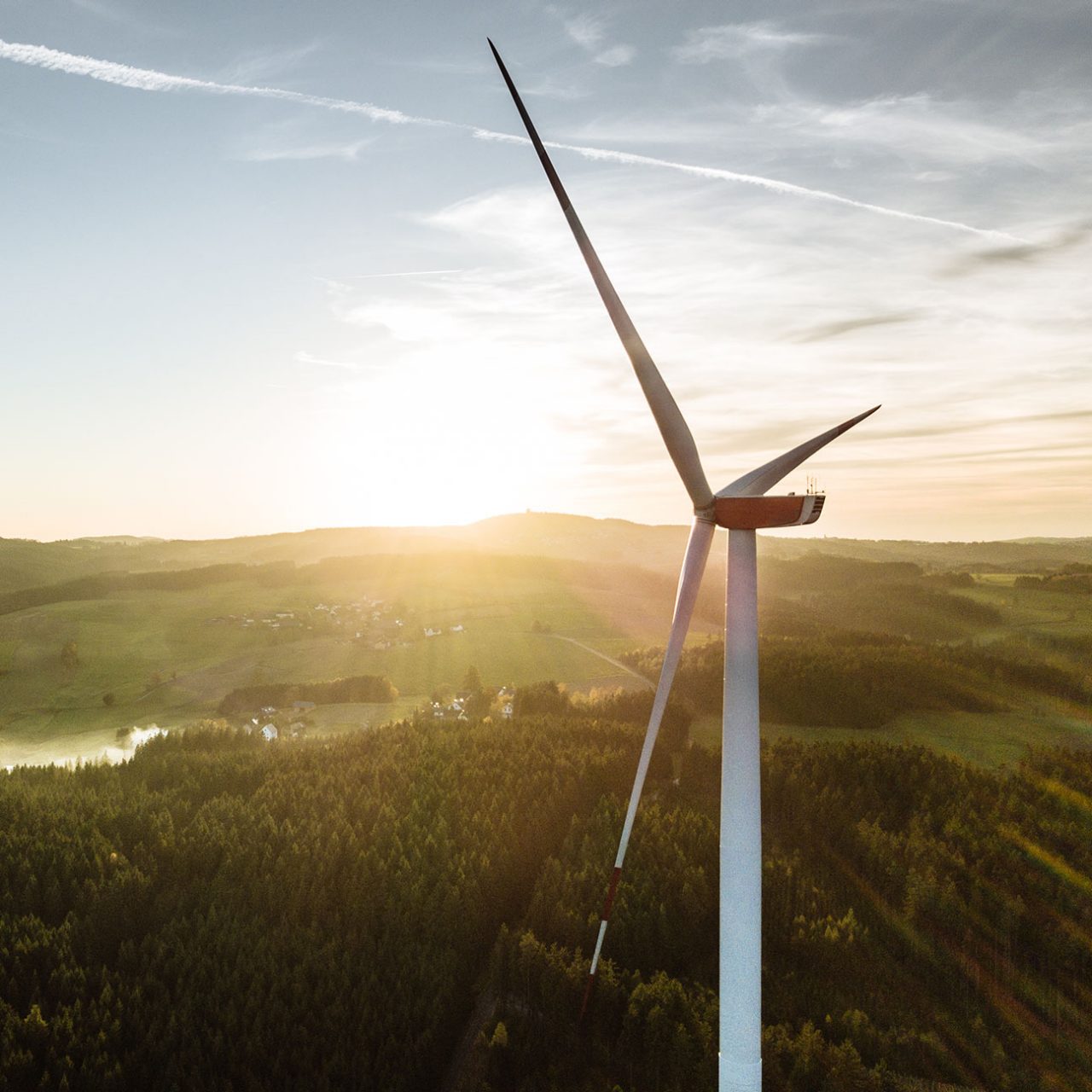 Aerial view of wind turbine in the sunset overlooking green fields