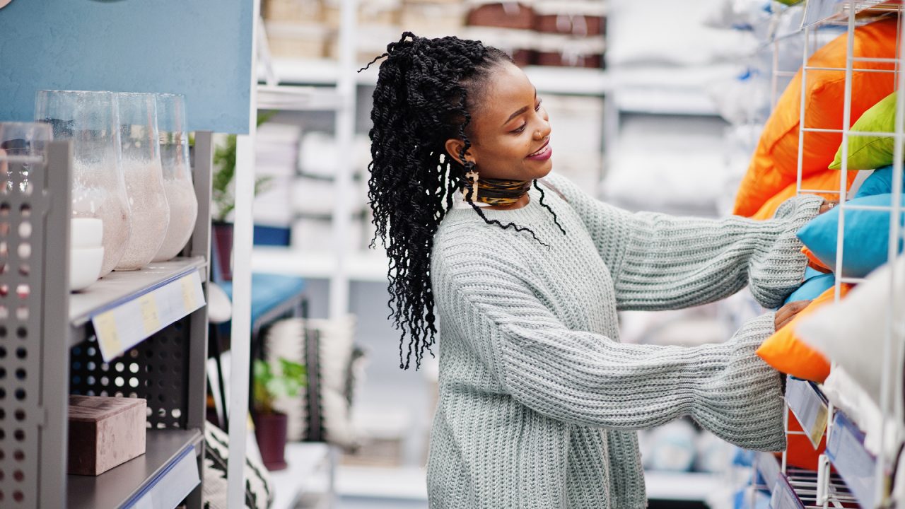 A young woman in a homeware store looking through of shelf of pillows 